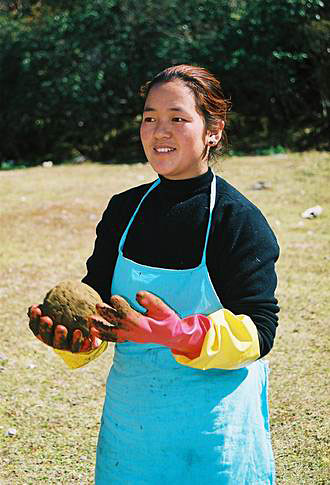
This young woman prepares yak dung for fuel.
